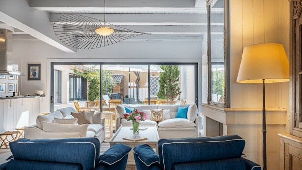 Ein modernes Wohnzimmer mit einer Sofagarnitur, einem Couchtisch mit Blumen und Blick auf die Terrassenanlage.