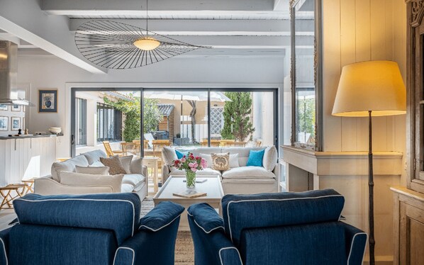 Ein modernes Wohnzimmer mit einer Sofagarnitur, einem Couchtisch mit Blumen und Blick auf die Terrassenanlage.