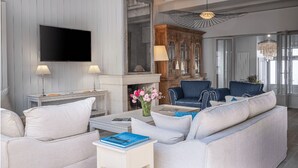 Una sala de estar moderna con un televisor de pantalla plana, dos lámparas, una chimenea y un sofá azul.