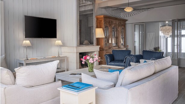 A modern living room with a flat-screen TV, two lamps, a fireplace, and a blue sofa.