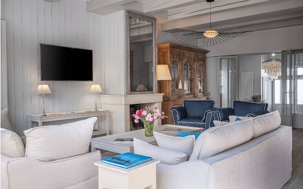 A modern living room with a flat-screen TV, two lamps, a fireplace, and a blue sofa.
