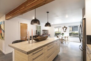 A modern kitchen with a large island, wooden cabinets, and pendant lighting. - The Elevation Haus- Modern Rattlesnake Abode (Missoula)