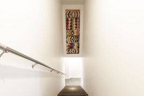 Eine Treppe mit Metallgeländer und einem gemusterten Wandbehang darüber.
