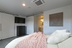 Ein Schlafzimmer mit Bett, Kommode, Fernseher und einem Gemälde an der Wand.