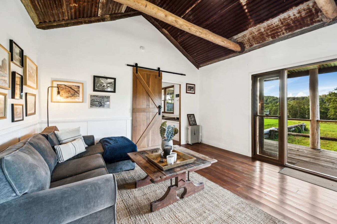 Amplia sala de estar con un ventanal grande, techo de madera y una zona de estar acogedora con sofá y mesa de centro.