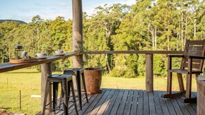 A wooden deck with a table and chairs, a potted plant, and a coffee maker. - The Hitching Rail Hut - Relax, Unwind & Reconnect (Coramba)