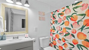 A bathroom with a white sink, a mirror with a gold frame, a toilet, and a shower curtain with a peach pattern. - Charming 3-bedroom house with WiFi and AC in marvelous Atlanta (Atlanta)