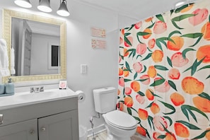 A bathroom with a white sink, a mirror with a gold frame, a toilet, and a shower curtain with a peach pattern. - Charming 3-bedroom house with WiFi and AC in marvelous Atlanta (Atlanta)