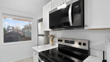 A modern kitchen with a built-in microwave, oven, and a window overlooking a residential area.