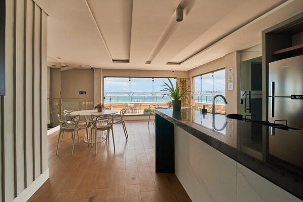 Eine moderne Küche mit einer großen Kochinsel, ein Essbereich mit Meerblick und ein Balkon mit Geländer.