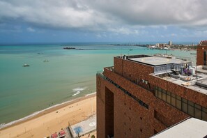 Ein Hochhaus mit Dachterrasse mit Blick auf einen Strand und das Meer.