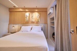 Ein Hotelzimmer mit einem großen Bett, einem hölzernen Kopfteil, Wandbildern, einem Nachttisch mit Lampe und einer Klimaanlage.