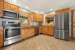 Cocina moderna con armarios de madera, electrodomésticos de acero inoxidable y piso de ladrillo.