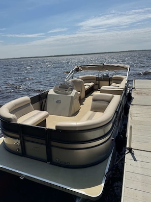 Un barco con zona de estar cubierta, timón y motor.