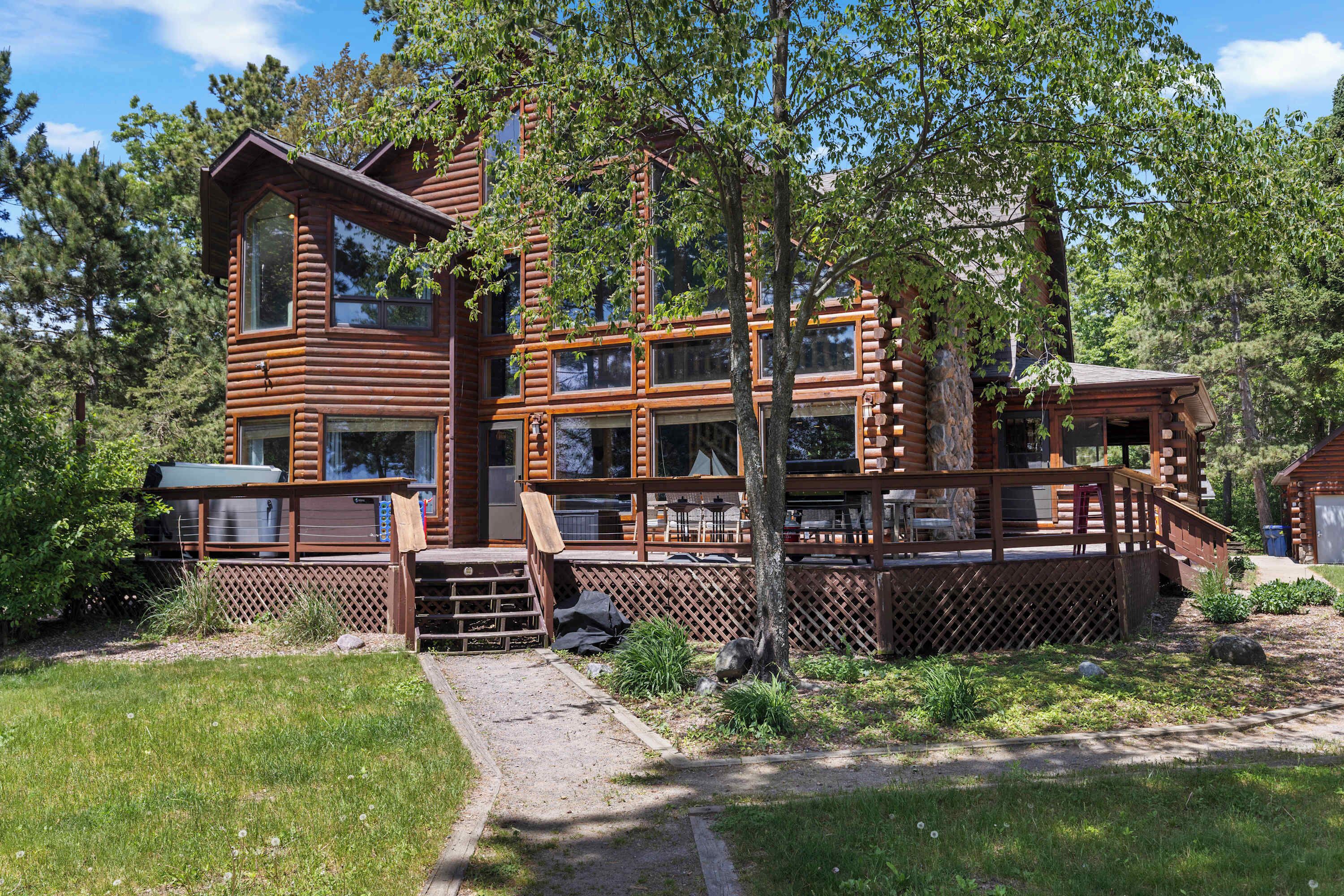 A multi-story log cabin with a deck and outdoor seating area.
