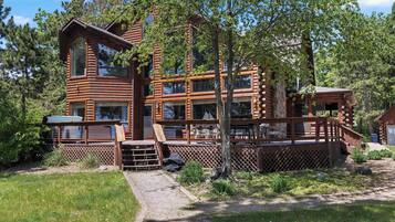 A multi-story log cabin with a deck and outdoor seating area.