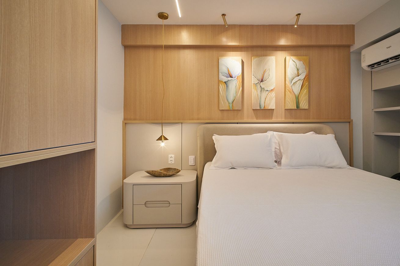 A bedroom with a bed, bedside table, and wall-mounted artwork.