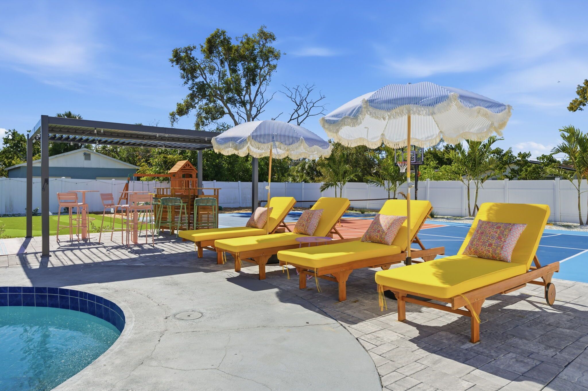 A poolside area with yellow lounge chairs, a covered seating area, and umbrellas.