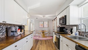 A modern kitchen with white cabinets, a wooden countertop, a coffee machine, a microwave, and a sink. - Pastel Palms | Resort Pool, Hot Tub & Sport Court (Bradenton)