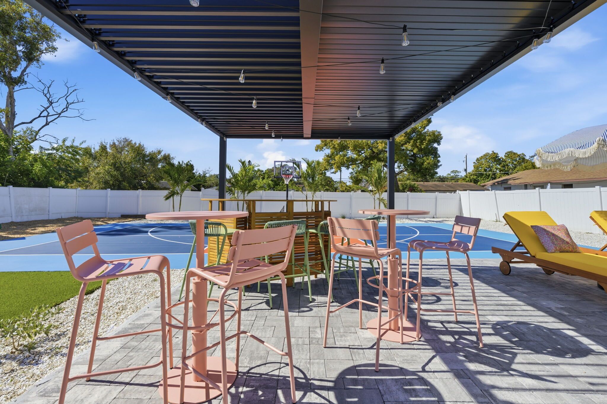 Une terrasse extérieure dotée d’un terrain de basket, d’un espace salon et d’une partie abritée avec des tables et des chaises.