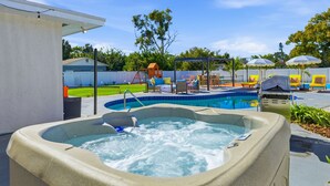 A hot tub with a pool, outdoor furniture, and a swing set. - Pastel Palms | Resort Pool, Hot Tub & Sport Court (Bradenton)