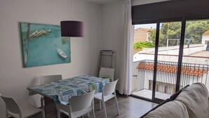 Zona pranzo con tavolo e sedie, un divano, un quadro e vista esterna.