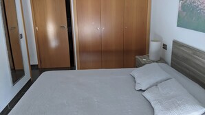 Una camera da letto con un letto grande, un armadio in legno, un comodino con una lampada e un quadro appeso al muro.