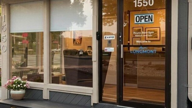 A building with a large glass door, a sign reading 'OPEN', and the number '1550'. - Cozy Queen Room on Main Street in Longmont (Longmont)