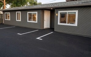 A motel with a parking lot, a single-story building, and a door. - Cozy Queen Room on Main Street in Longmont (Longmont)