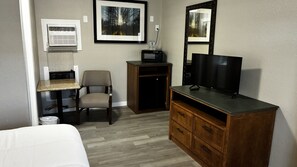 A hotel room with a bed, a desk with a computer, a chair, a television, a dresser, and a microwave. - Cozy Queen Room on Main Street in Longmont (Longmont)