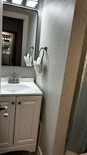 A bathroom with a white sink, a mirror, a towel ring, and a textured wall. - Cozy Queen Room on Main Street in Longmont (Longmont)
