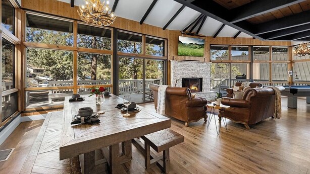 Un salon spacieux avec une cheminée, des canapés en cuir et une grande table à manger en bois.