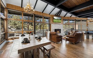 Un salon spacieux avec une cheminée, des canapés en cuir et une grande table à manger en bois.