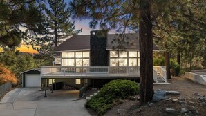 Une maison moderne à deux étages, dotée d’une façade en pierre, de grandes fenêtres et d’un porche abrité.