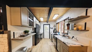 Une cuisine moderne avec un plancher en bois, des armoires blanches et un meuble à vin intégré.