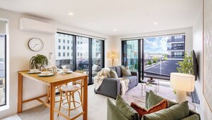A modern living room with a dining area, large windows, and a view of the city. - Stylish & Central - City View Apt w/ Free Carpark (Christchurch)