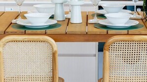 A dining area with a wooden table set for four, surrounded by wicker chairs. - Stylish & Central - City View Apt w/ Free Carpark (Christchurch)