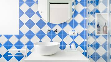 Une salle de bain avec un lavabo blanc, un miroir et des carreaux bleus à motifs losangés.