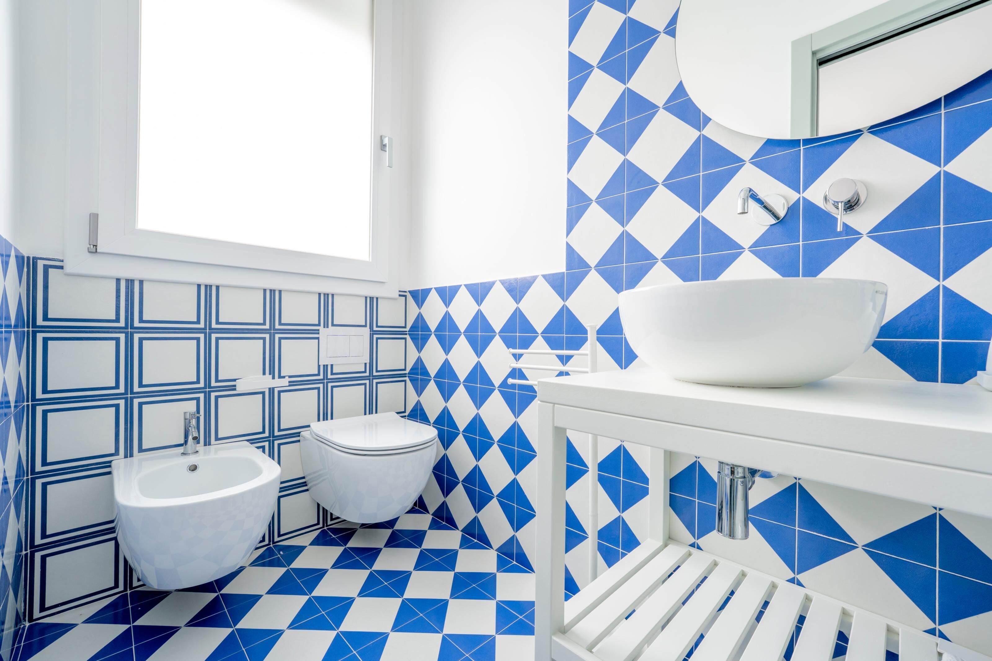 A bathroom with a white sink, a bidet, and a mirror.