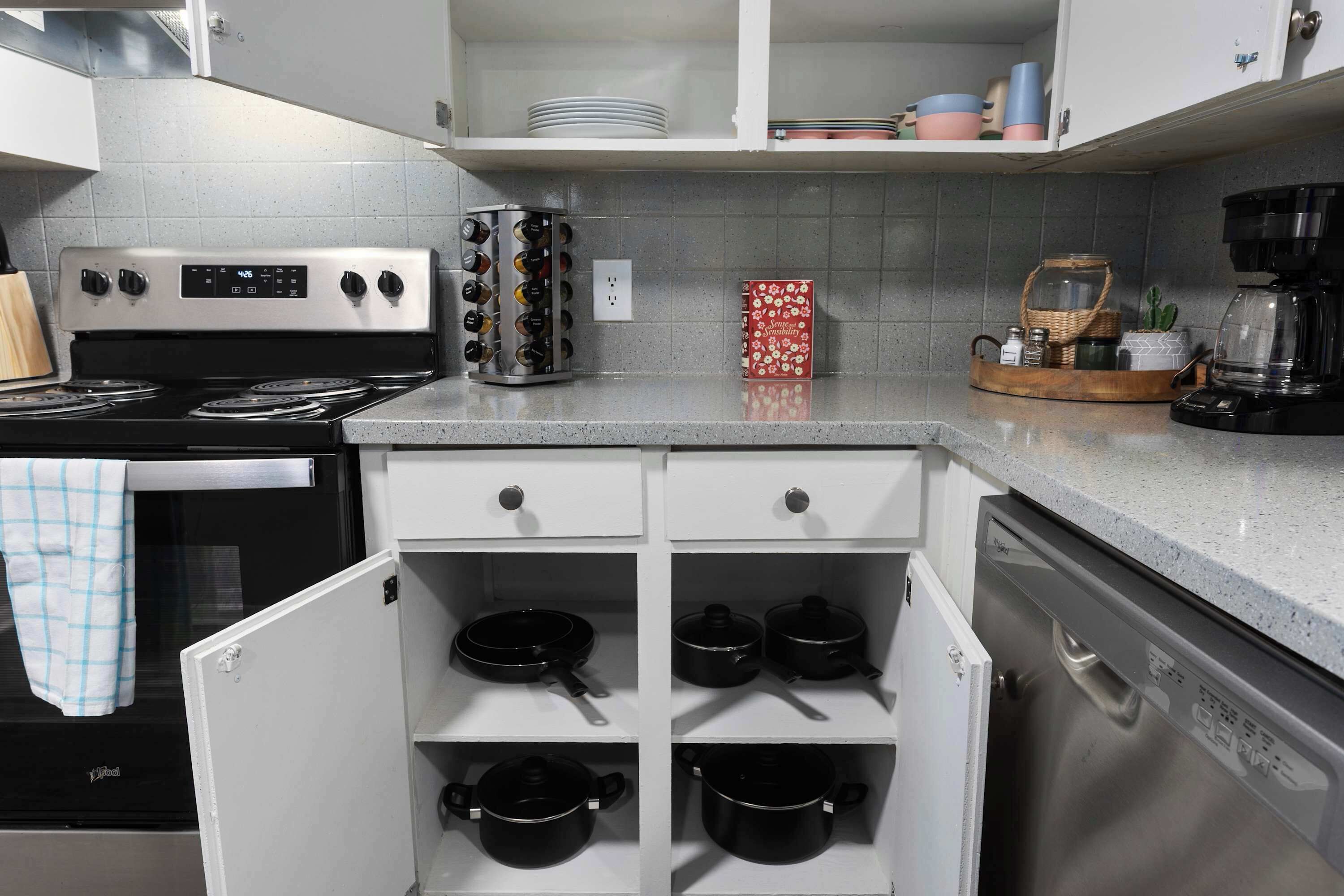 Una cocina compacta con estufa, cafetera y lavavajillas.