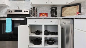 A kitchen with white cabinets, a stainless steel stove, a coffee maker, and a framed map on the countertop. - Chief Themed 2 BR APT_KingBeds_Near Dining (Kansas City)