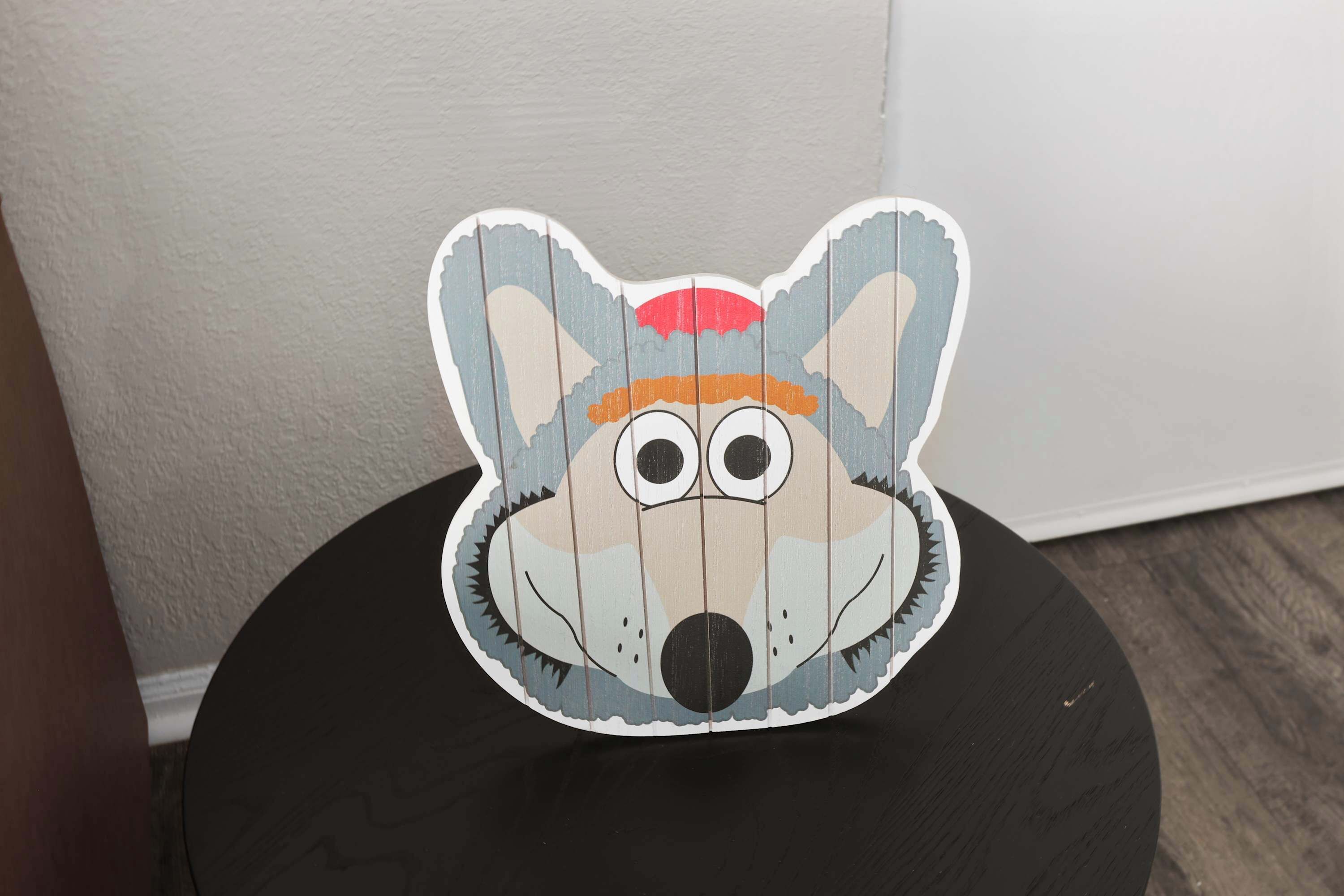 A round table with a wooden texture and a cartoon character cutout on top.