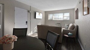 Un salon moderne comprenant une table à manger, un canapé et un téléviseur fixé au mur.