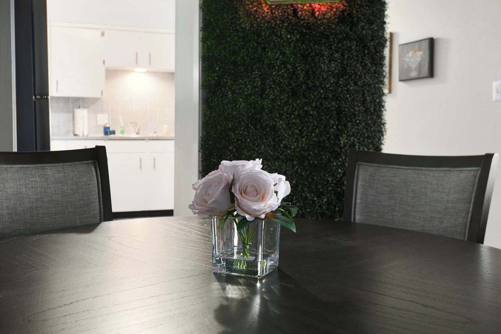 Et spisebord med en blomstervase i midten, omgivet af stole.