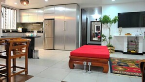 A modern kitchen with stainless steel appliances, a dining area with wooden chairs, a red sofa, and a TV on the wall. - Lavish Lodge -2 Bedrooms 2 Bath (Suva)