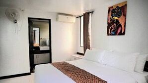 A hotel room with a bed, a bedside table, a mirror, an air conditioning unit, and a window with curtains. - Lavish Lodge -2 Bedrooms 2 Bath (Suva)