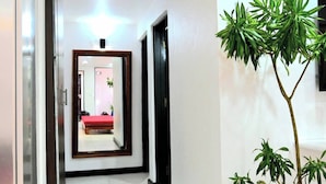 A hallway with a mirror reflecting a room, a potted plant, and a red carpet. - Lavish Lodge -2 Bedrooms 2 Bath (Suva)