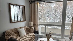 En moderne stue med et stort vindue, en sofa, et sofabord og et spisebord.