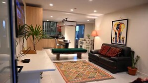 A modern living room with a pool table, a black leather sofa, and a colorful rug. - Lavish Lodge (Suva)