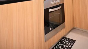 A modern kitchen with wooden cabinets, a stainless steel stove, a microwave, and a built-in oven. - Lavish Lodge (Suva)
